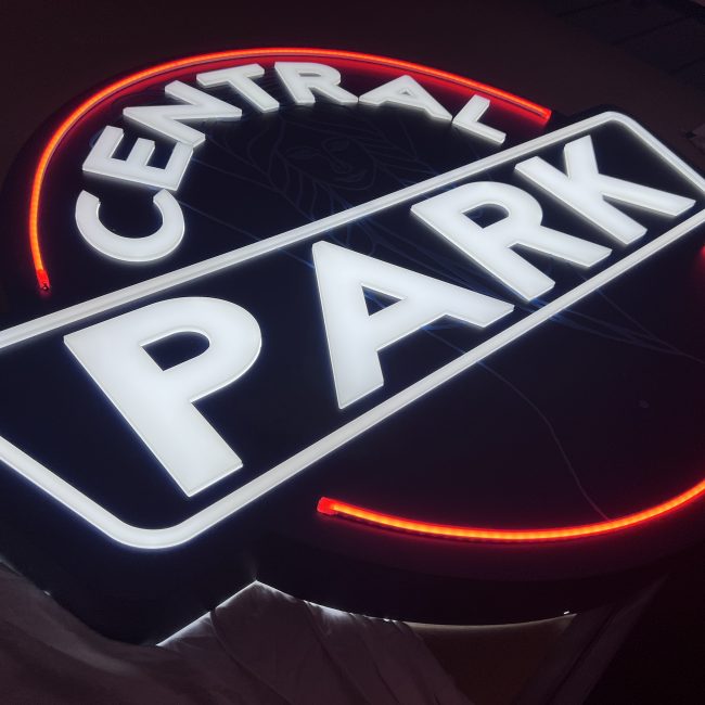 a photo of the central park illuminated sign, glowing red and white in the dark