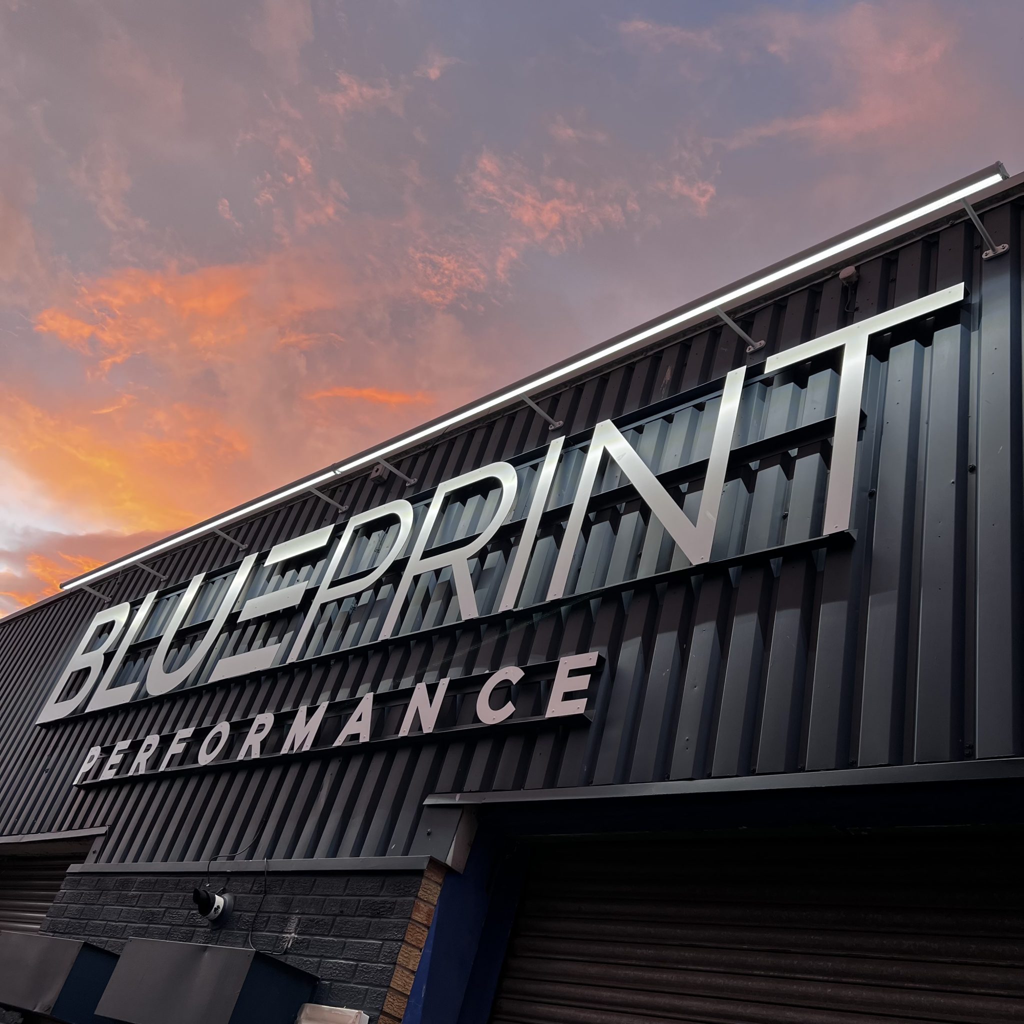 A photo of the Blueprint Performance main facia from the right, complete with its new industrial style signage and a long horizontal light bar to illuminate the new signage in the evenings